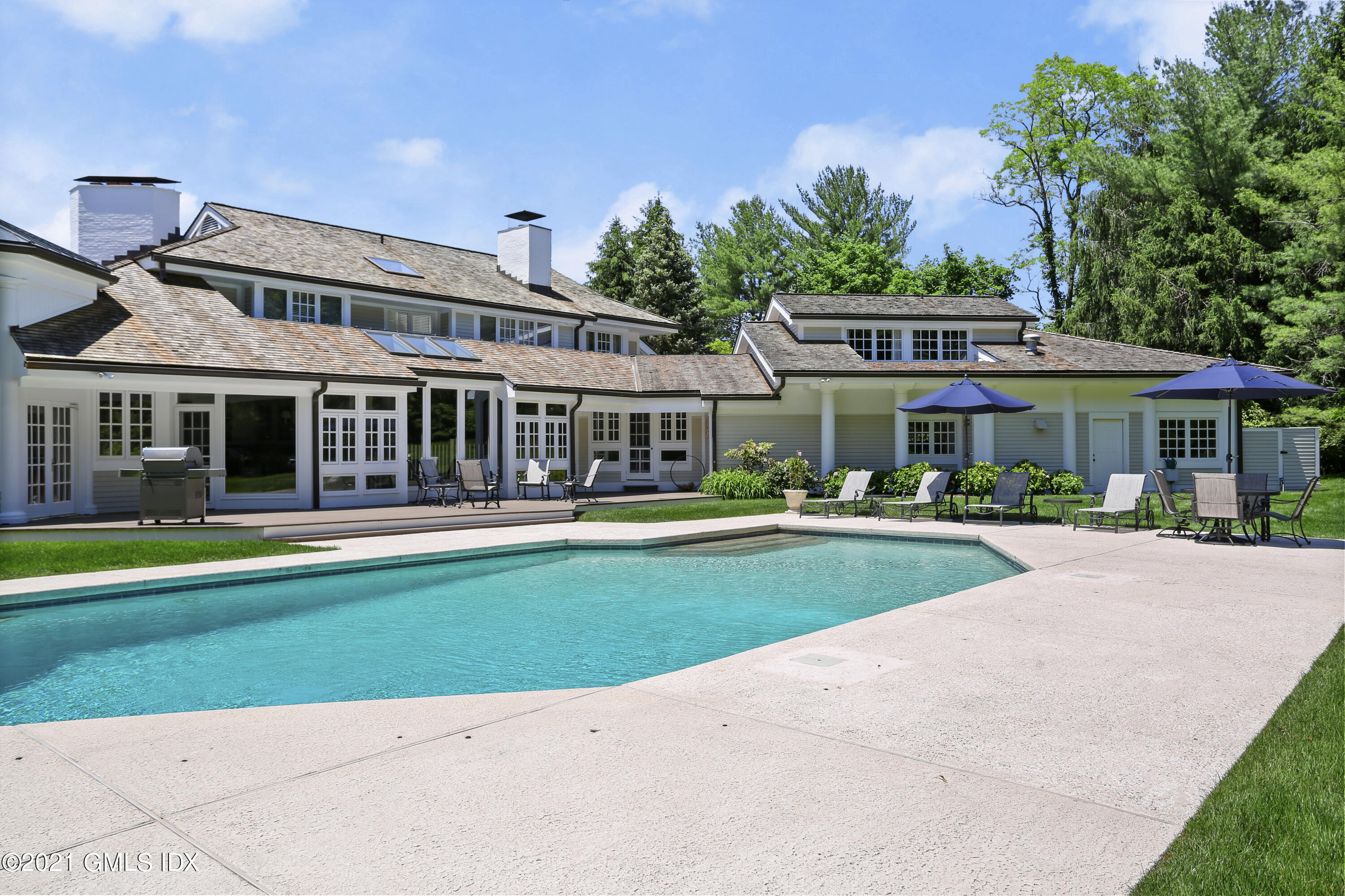 557 Round Hill Road Greenwich, CT 06831 - Photo 20 of 26 a front view of a house with a yard table and chairs
