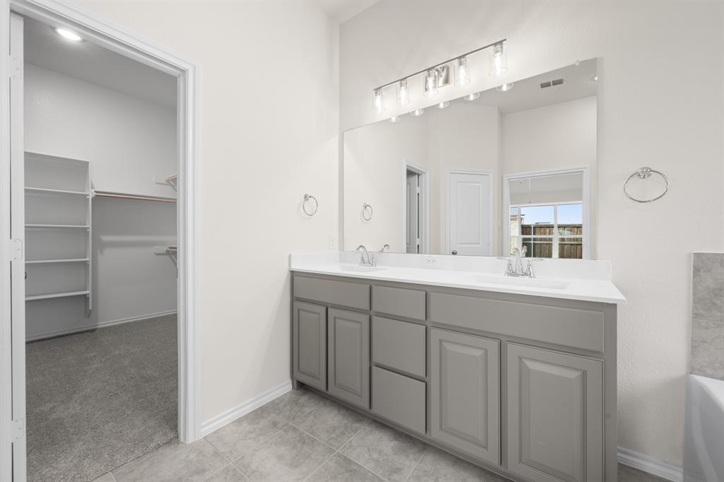 810 Misty Lane Cleburne, TX 76033 - Photo 16 of 30 a bathroom with a double vanity sink a mirror and a shower
