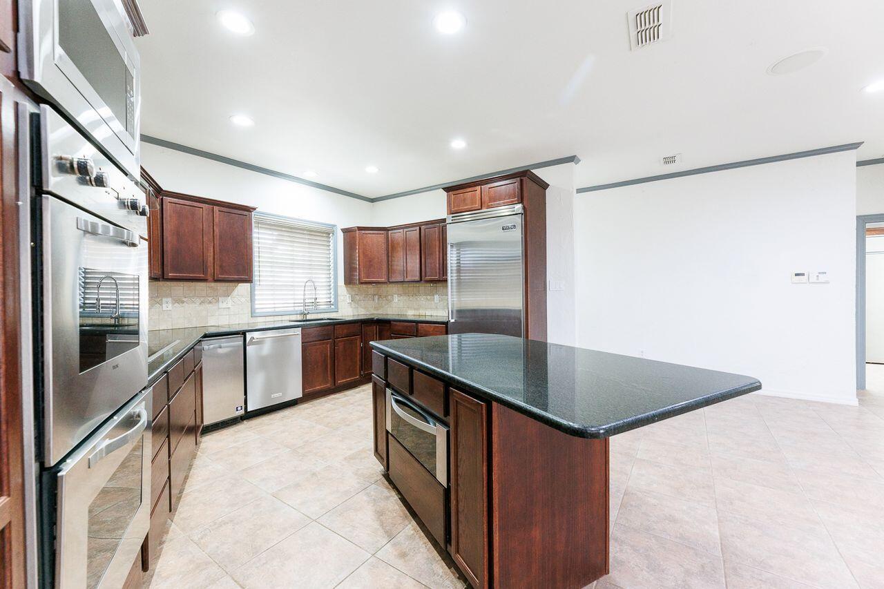 5811 11th Place, Unit 9 Lubbock, TX 79416 - Photo 13 of 50 a kitchen with stainless steel appliances granite countertop a sink and a refrigerator