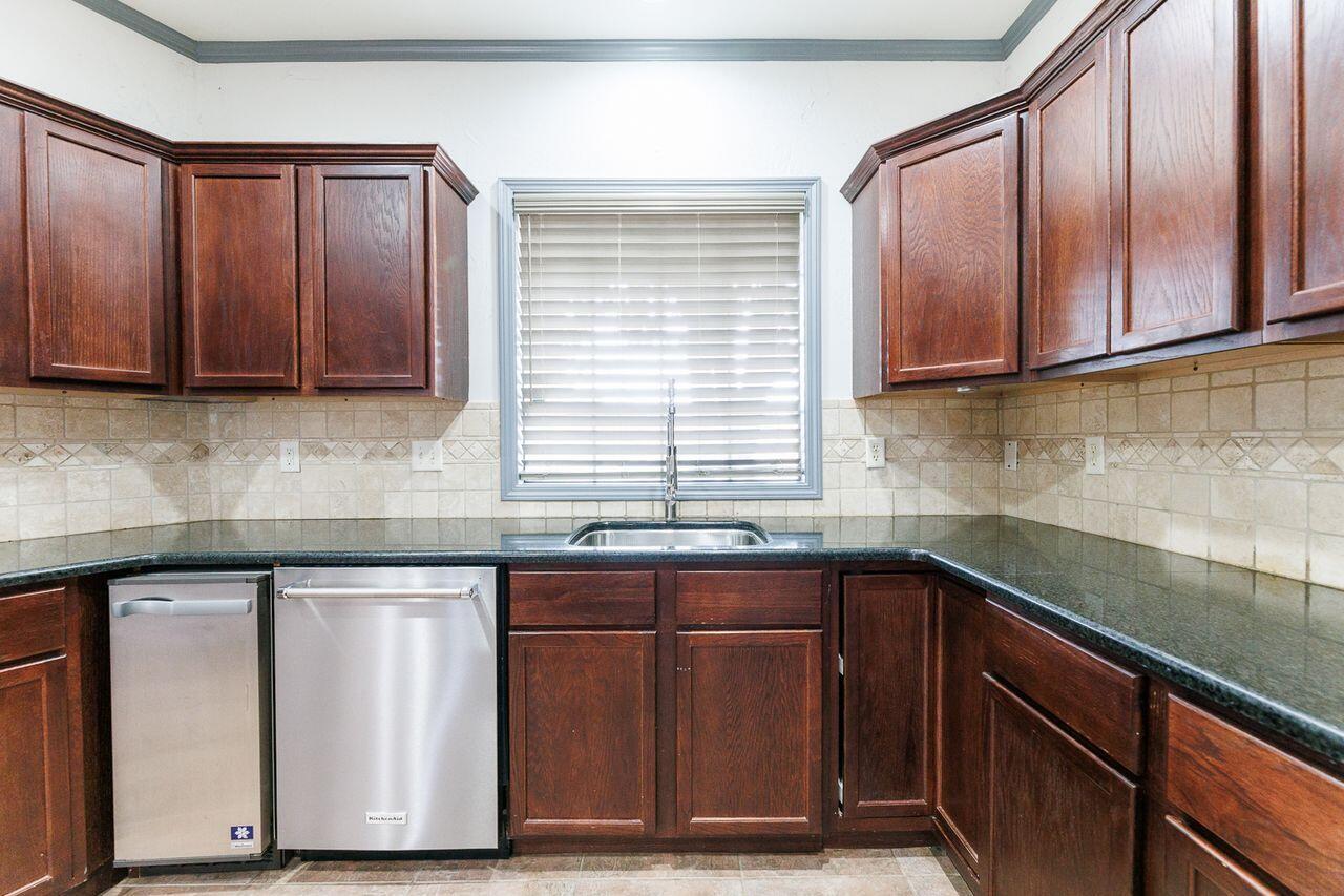 5811 11th Place, Unit 9 Lubbock, TX 79416 - Photo 16 of 50 a kitchen with wooden cabinets and a sink