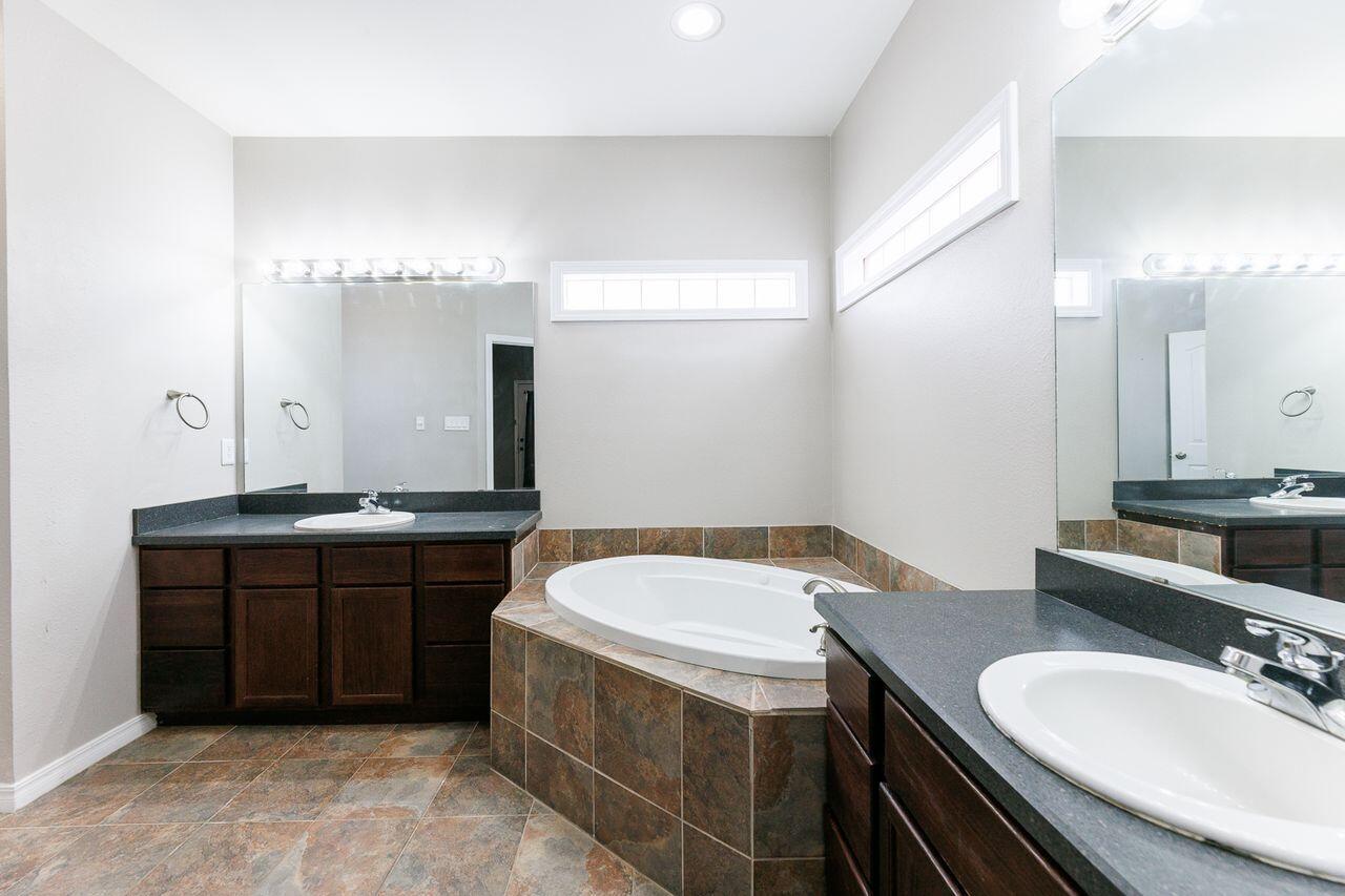 5811 11th Place, Unit 9 Lubbock, TX 79416 - Photo 38 of 50 a bathroom with a granite countertop sink and a mirror