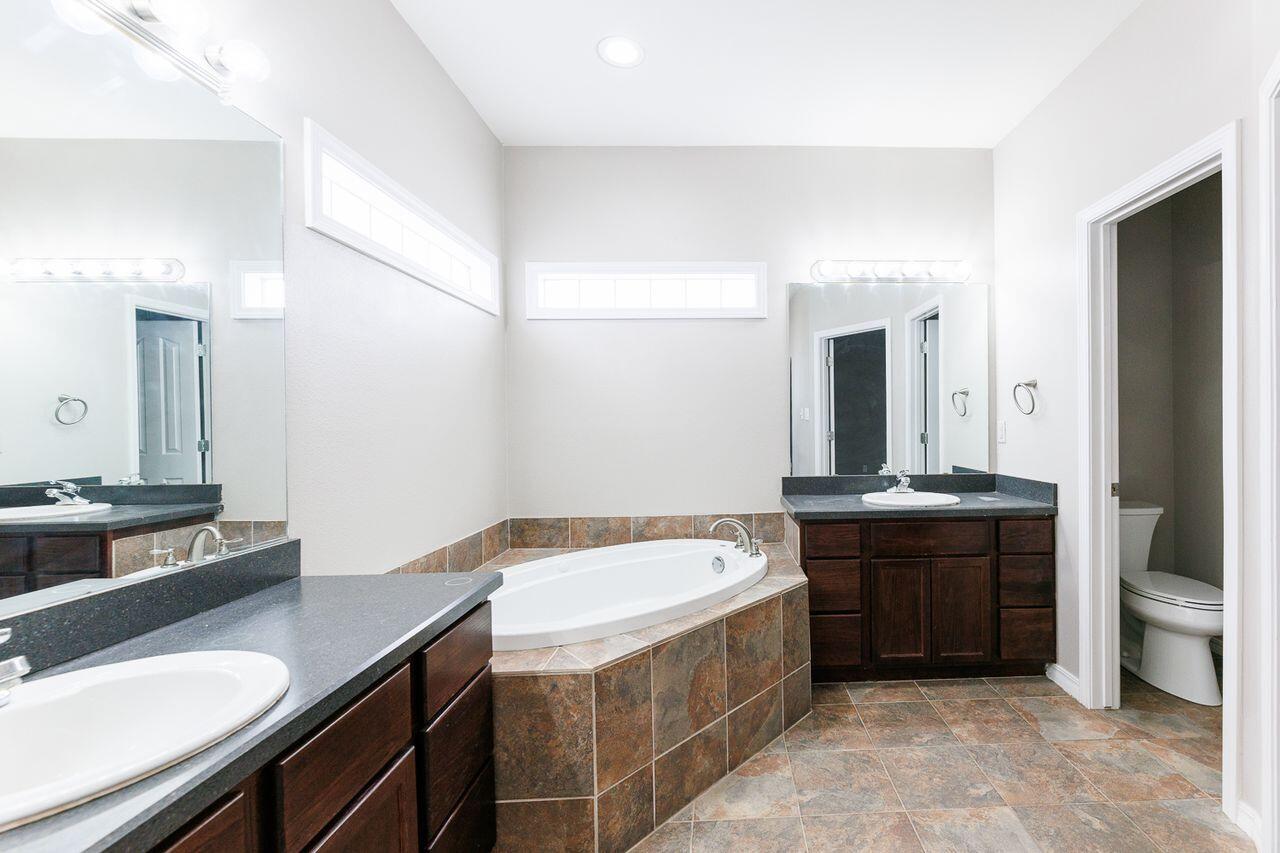 5811 11th Place, Unit 9 Lubbock, TX 79416 - Photo 40 of 50 a spacious bathroom with a granite countertop sink and a mirror
