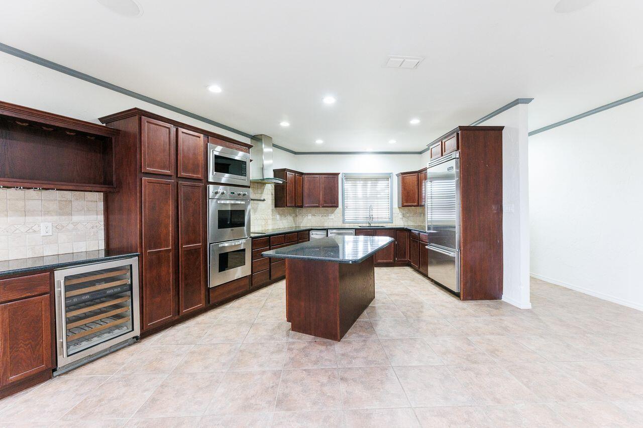 5811 11th Place, Unit 9 Lubbock, TX 79416 - Photo 8 of 50 a kitchen with a refrigerator and a wooden cabinets