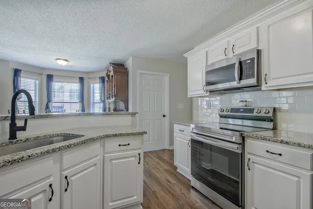 a kitchen with stainless steel appliances granite countertop a stove microwave and sink