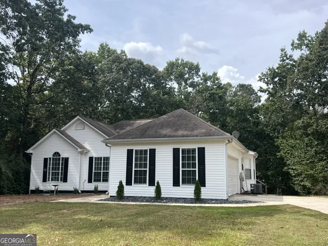 a front view of house with yard and trees in the background