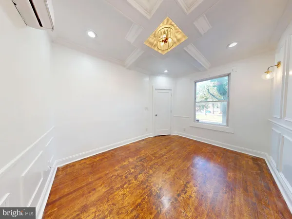 an empty room with a wooden floor and natural light