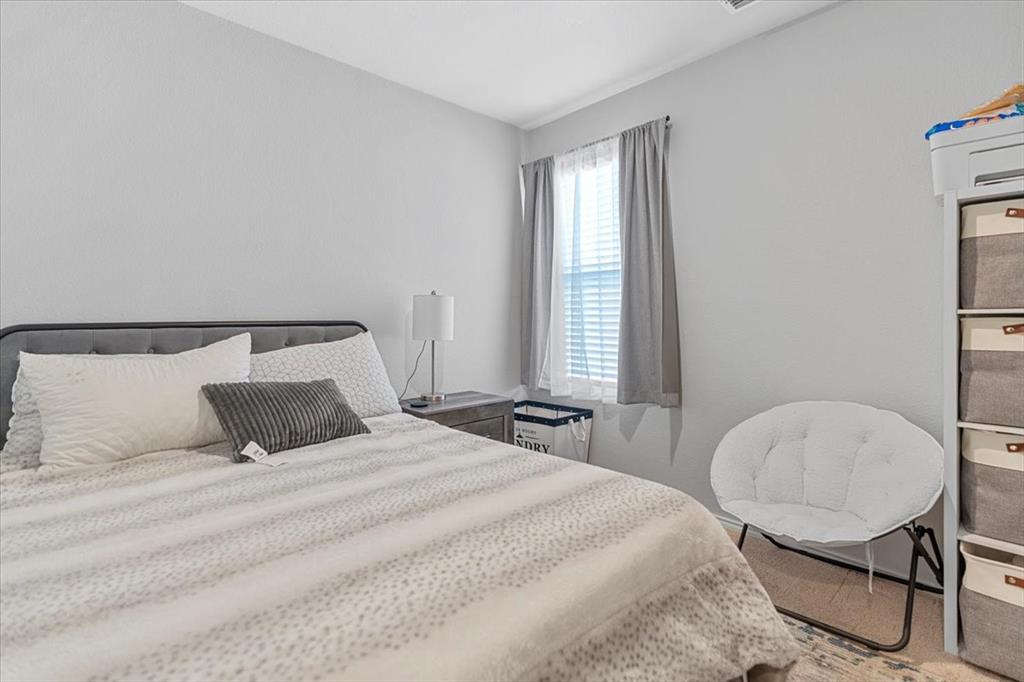 8730 Texas Risinger Drive Fort Worth, TX 76123 - Photo 18 of 19 a bedroom with a bed a chair and windows
