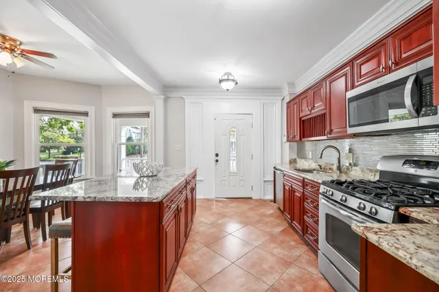 a kitchen with stainless steel appliances granite countertop a stove top oven a sink dishwasher a dining table and chairs with wooden floor