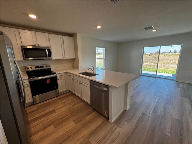 a kitchen with a sink wooden floor and black appliances