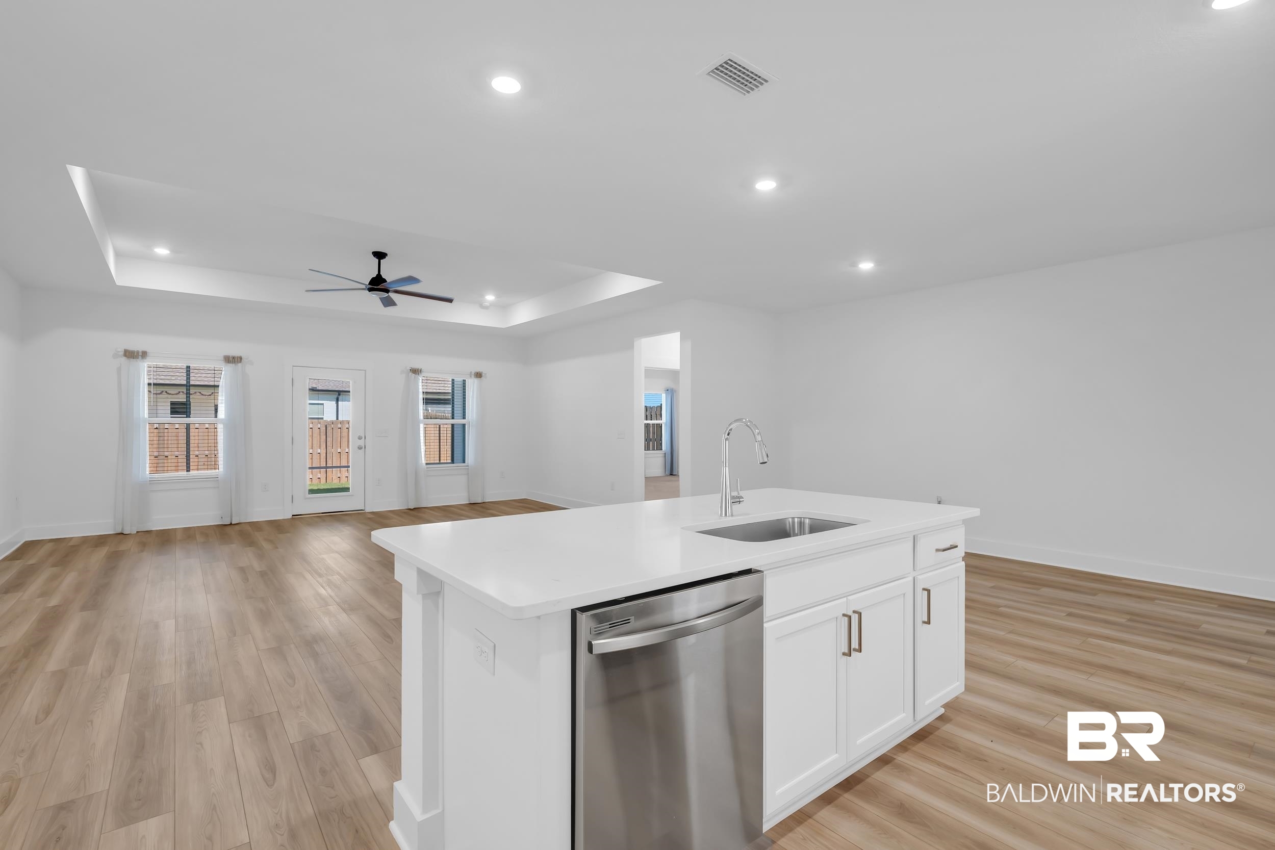 9933 Weller Cove Foley, AL 36535 - Photo 14 of 36 Kitchen island with a stainless steel sink and gooseneck faucet, white shaker cabinetry, and a stainless steel dishwasher