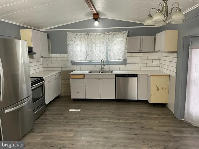 a kitchen with stainless steel appliances a sink cabinets and wooden floor