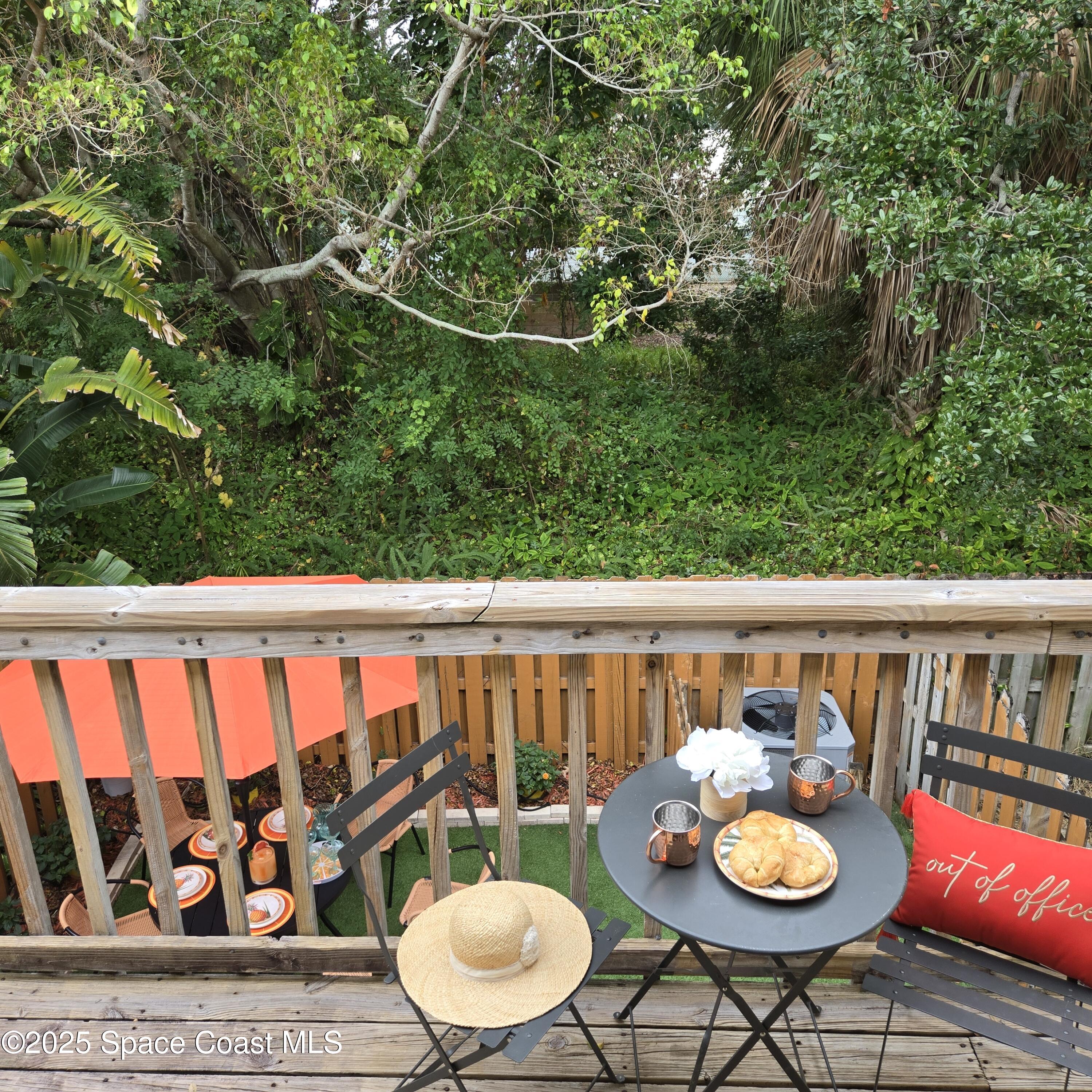 8761 Ilex Court Cape Canaveral, FL 32920 - Photo 19 of 41 a balcony with wooden floor and some trees
