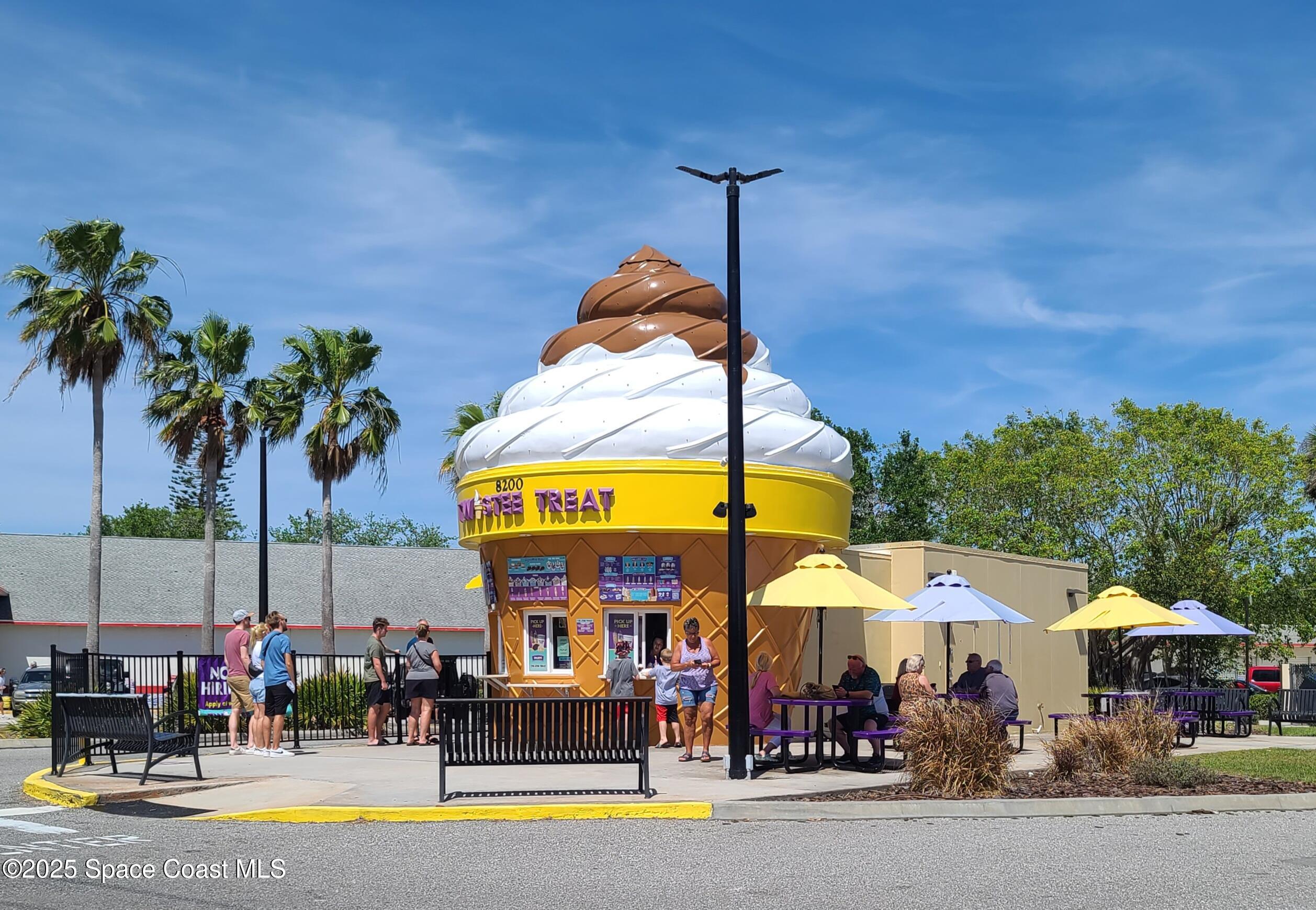 8761 Ilex Court Cape Canaveral, FL 32920 - Photo 41 of 41 a group of people sitting under an umbrella in front of retail shop