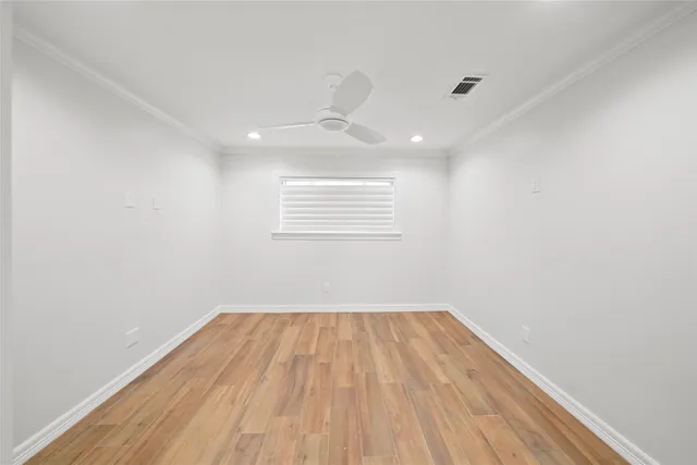 a view of empty room with wooden floor and fan