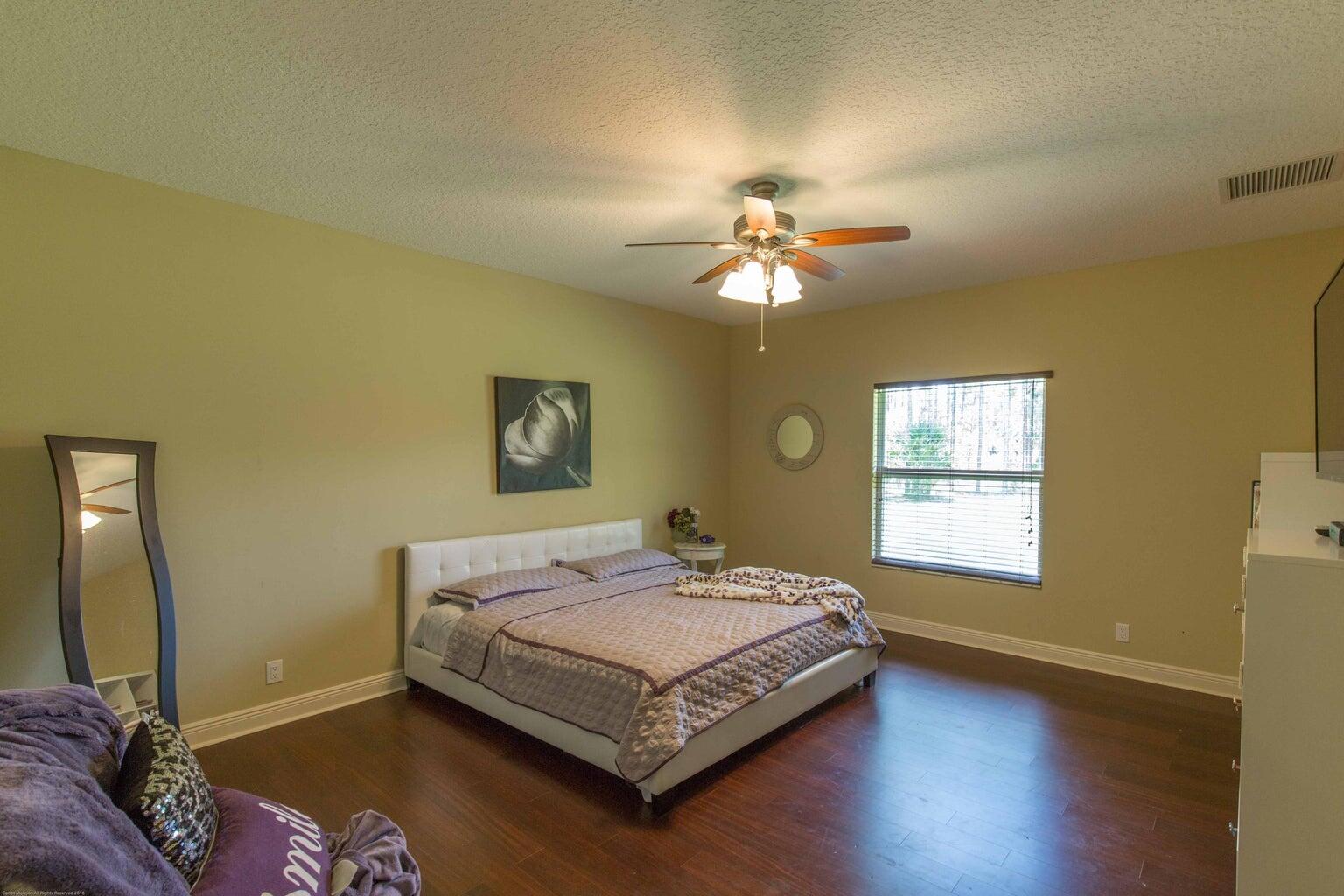14816 Stirrup Lane Wellington, FL 33414 - Photo 20 of 30 a bedroom with a bed chandelier and a window