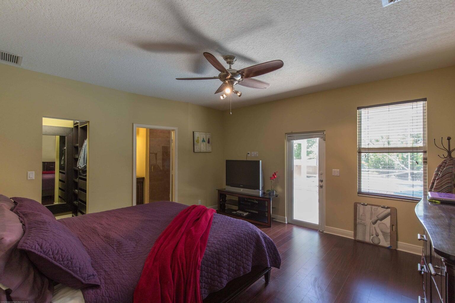 14816 Stirrup Lane Wellington, FL 33414 - Photo 21 of 30 a bedroom with a bed and a chandelier