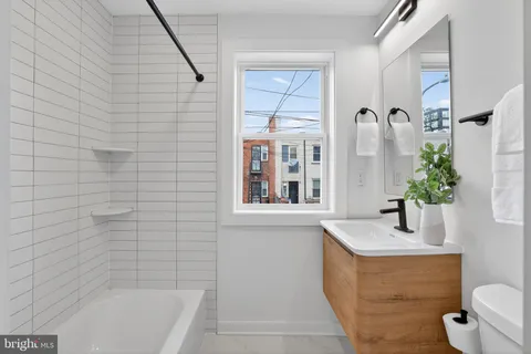 a bathroom with a granite countertop sink a toilet and shower