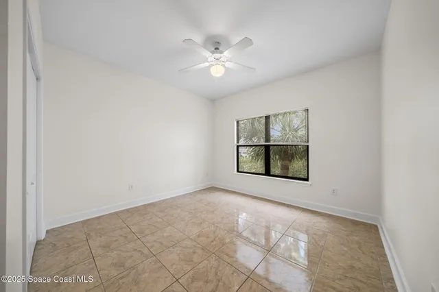 an empty room with a ceiling fan and a window