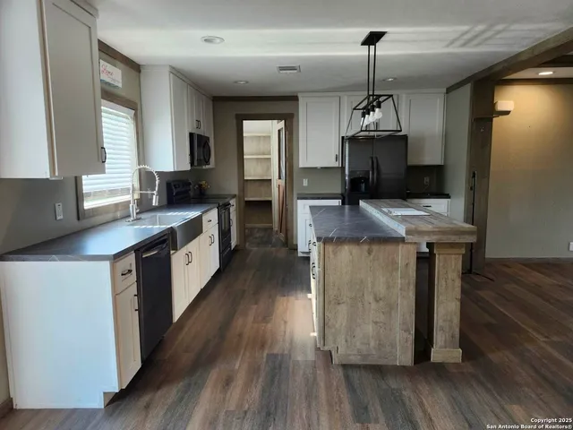 a kitchen with kitchen island granite countertop wooden floors and white cabinets