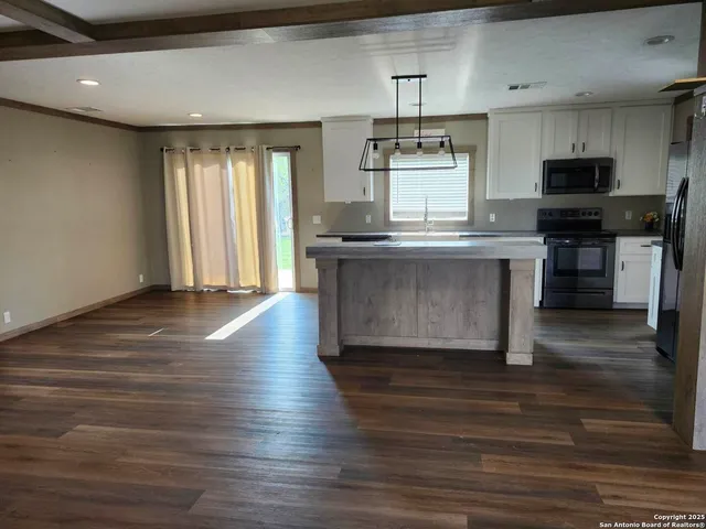 a kitchen with kitchen island granite countertop a sink cabinets and wooden floor