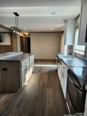 a kitchen with stainless steel appliances granite countertop a sink a stove and a wooden floors