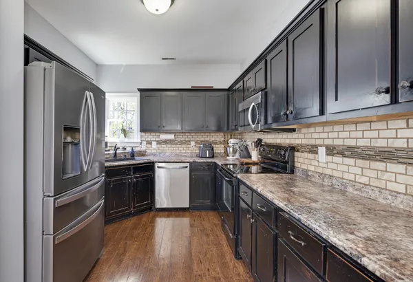 a kitchen with stainless steel appliances granite countertop a stove a sink dishwasher and a microwave oven on the granite countertops