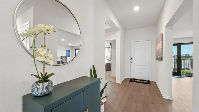 a view of a hallway with wooden floor and a chandelier fan