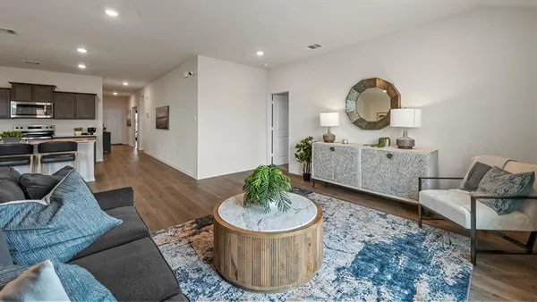 a living room with furniture a rug and kitchen view