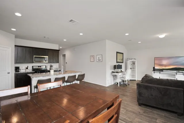 a living room with furniture a flat screen tv and kitchen view
