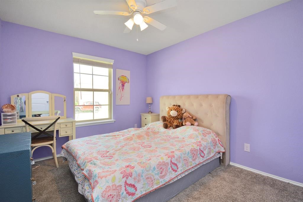 1602 Brownwood Ridge Court Richmond, TX 77469 - Photo 23 of 35 a bedroom with a bed and a chandelier