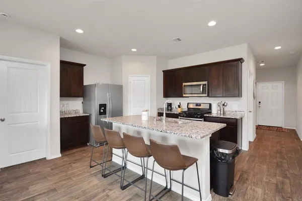 a kitchen with stainless steel appliances granite countertop a stove a sink a microwave a refrigerator and cabinets