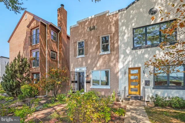 a front view of a multi story residential apartment building with yard and bench