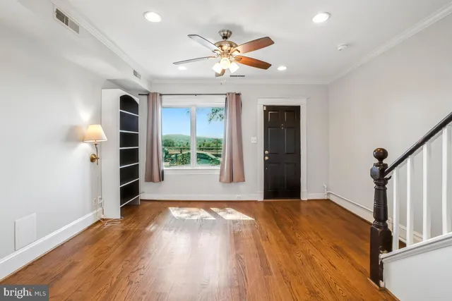 a view of an empty room with a window and wooden floor