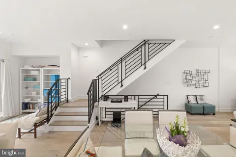 a living room with furniture a rug kitchen view and a table