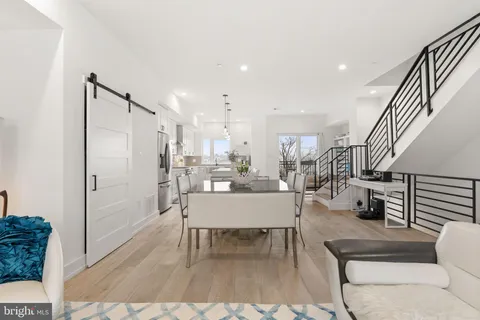 a kitchen with stainless steel appliances kitchen island granite countertop a refrigerator a stove a sink and white cabinets with wooden floor