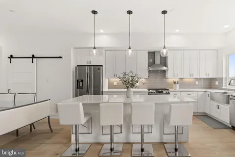 a large kitchen with stainless steel appliances kitchen island a large counter top a stove and a wooden floors