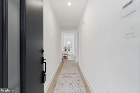 a view of a hallway with wooden floor and a bathroom