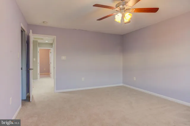 an empty room with a chandelier fan and windows
