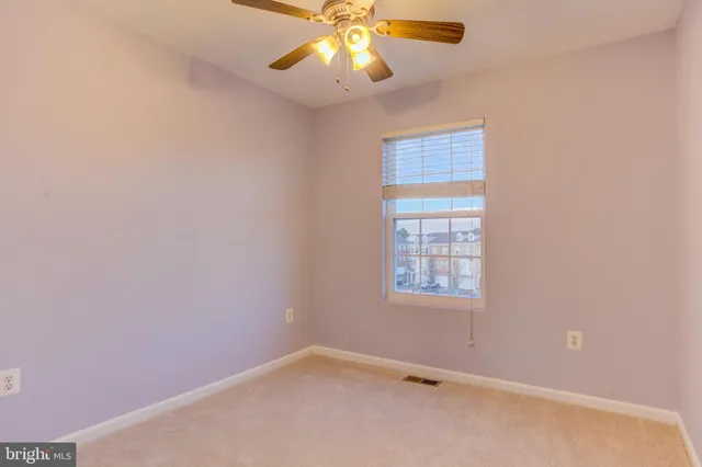 an empty room with windows and chandelier fan