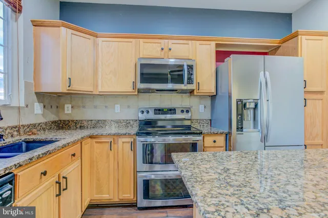a kitchen with stainless steel appliances granite countertop a stove a sink and a refrigerator