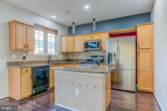 a kitchen with stainless steel appliances granite countertop a refrigerator a stove a sink and a microwave