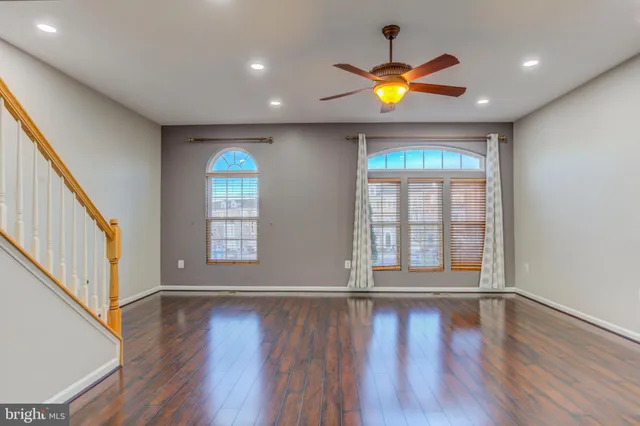 a view of empty room with wooden floor and fan