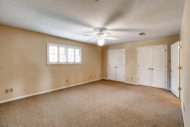 an empty room with windows and fan