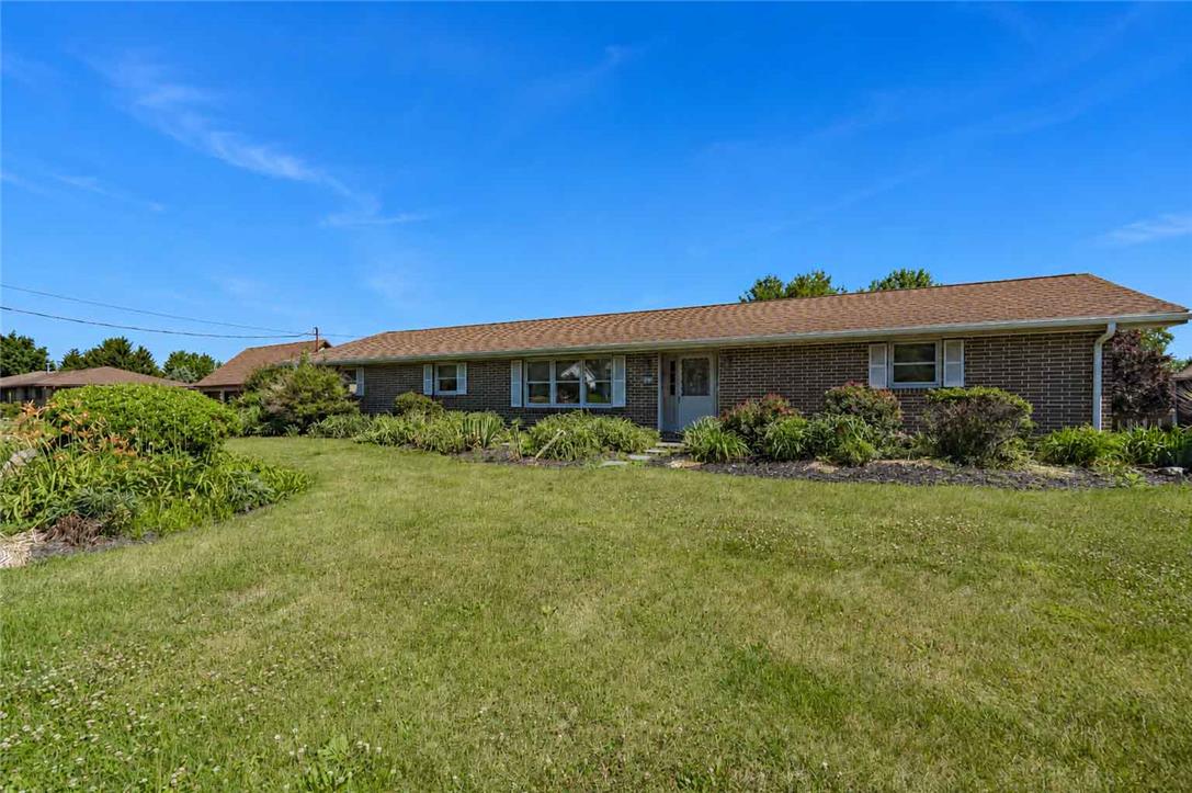 A well-maintained brick ranch home with neat landscaping, offering inviting curb appeal under a clear blue sky.