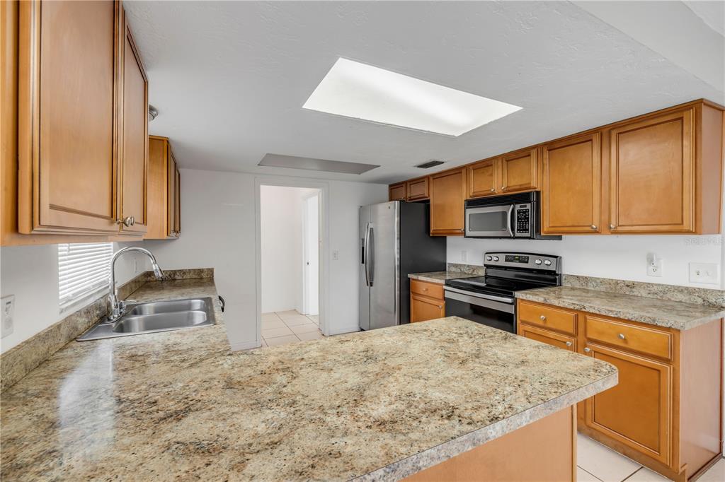 3132 Pine Tree Drive Edgewater, FL 32141 - Photo 12 of 32 a kitchen with stainless steel appliances granite countertop a sink stove microwave and refrigerator