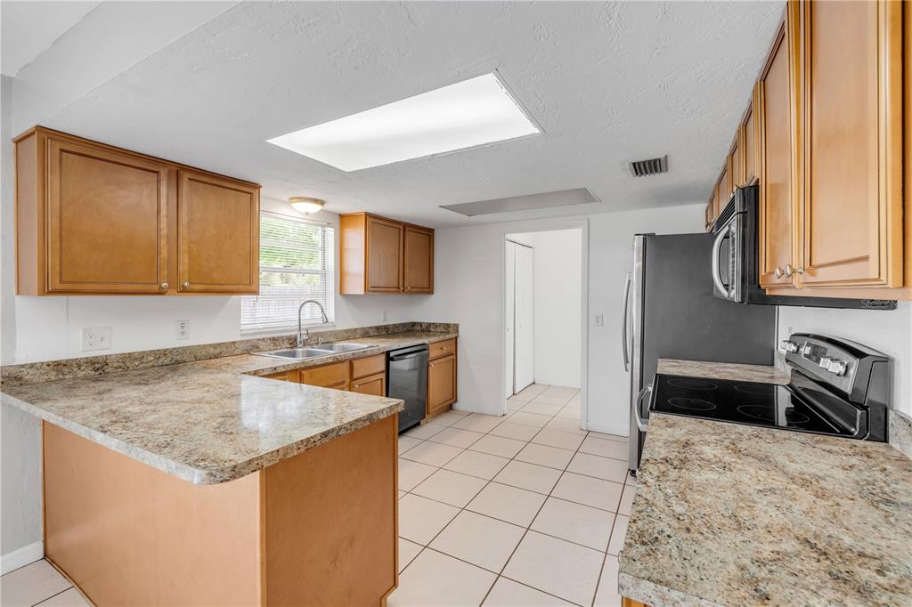 3132 Pine Tree Drive Edgewater, FL 32141 - Photo 13 of 32 a kitchen with granite countertop a sink and a stove top oven