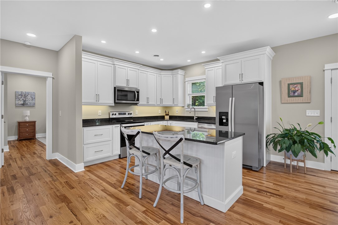 405 Pawnee Drive Walhalla, SC 29691 - Photo 8 of 36 A contemporary kitchen features bright white cabinetry, dark stone countertops, and polished hardwood flooring.