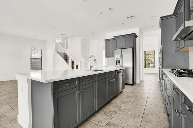 a large kitchen with stainless steel appliances a sink stove and cabinets