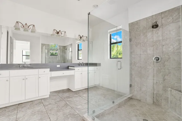 a spacious bathroom with a granite countertop sink a mirror and a shower