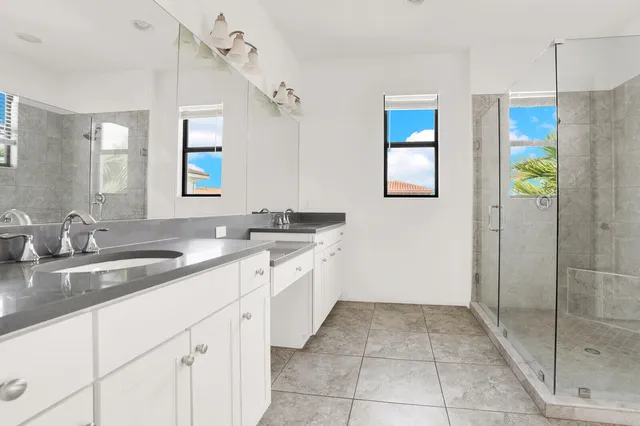 a spacious bathroom with a granite countertop sink a mirror and a shower